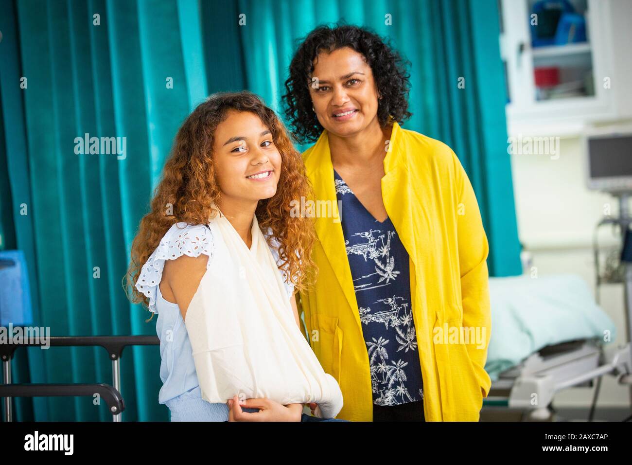 Porträt lächelnde Mutter und Tochter mit Arm in Schlinge im Krankenhaus Stockfoto