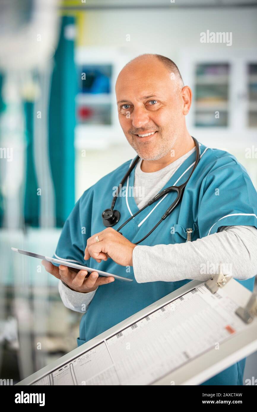 Lächelnder, selbstbewusster Hausarzt mit digitaler Tablette im Krankenhaus Stockfoto