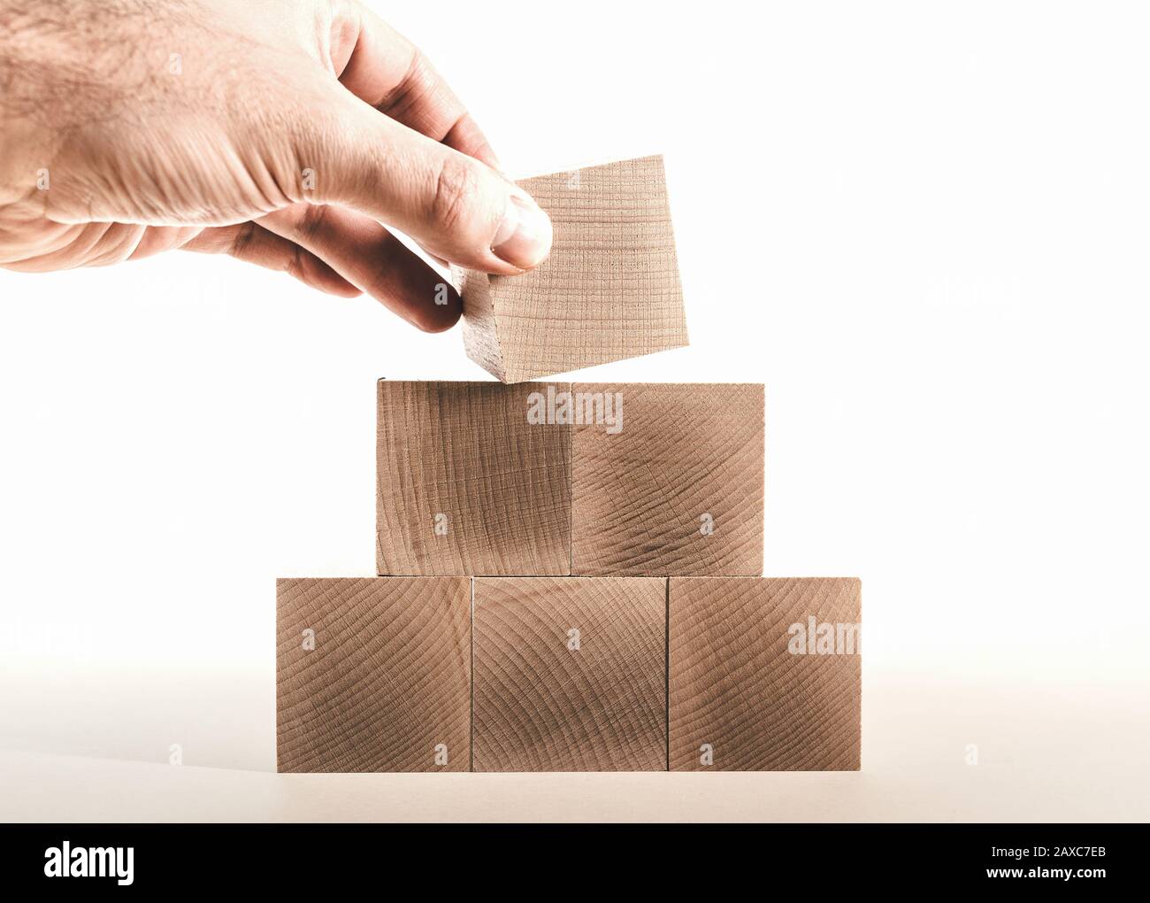 Händigen Sie den letzten Holzblock auf die Pyramide, das Unternehmenswachstum Konzept Stockfoto