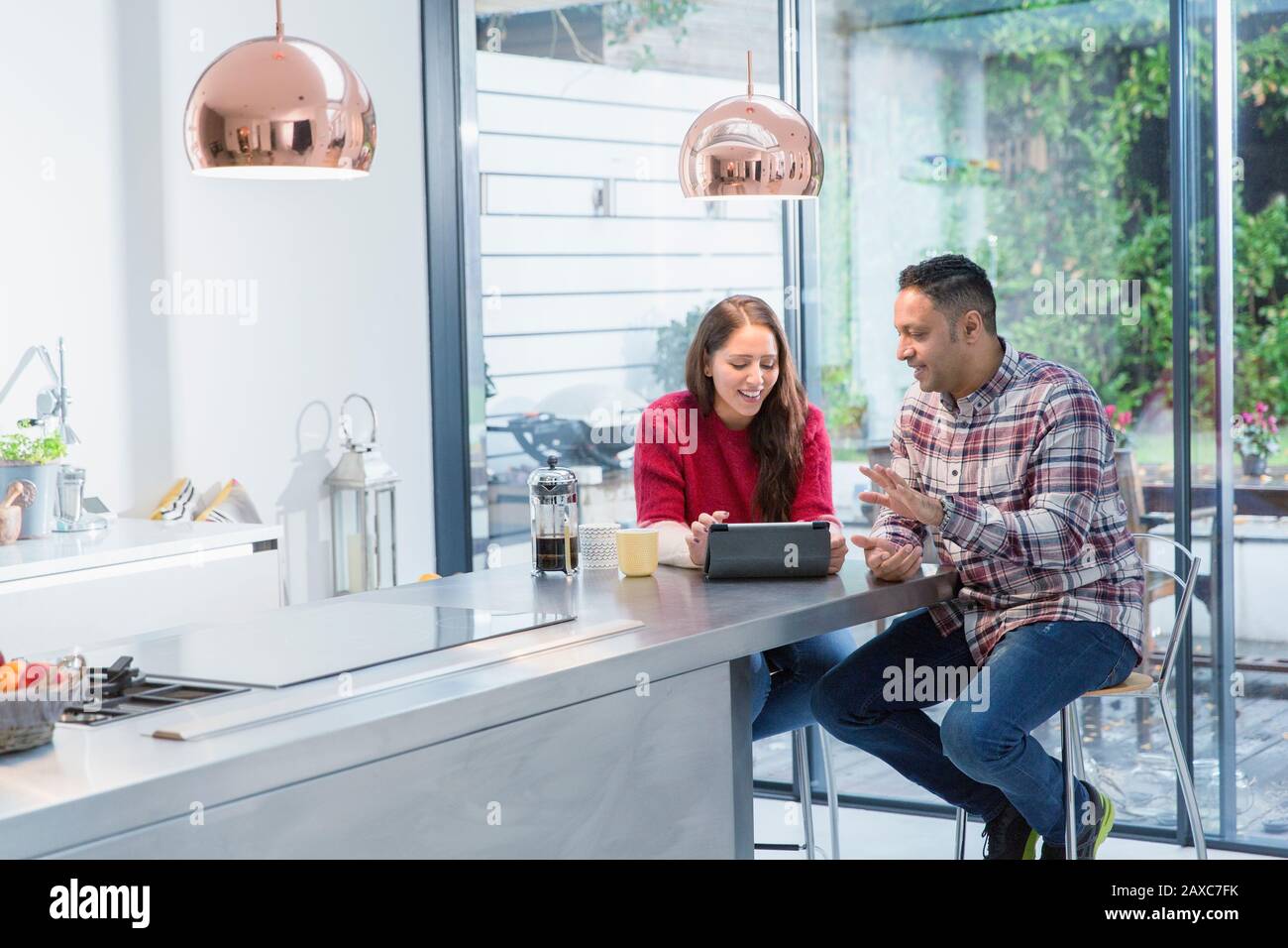 Ein Paar, das digitale Tabletts auf der Kücheninsel verwendet Stockfoto