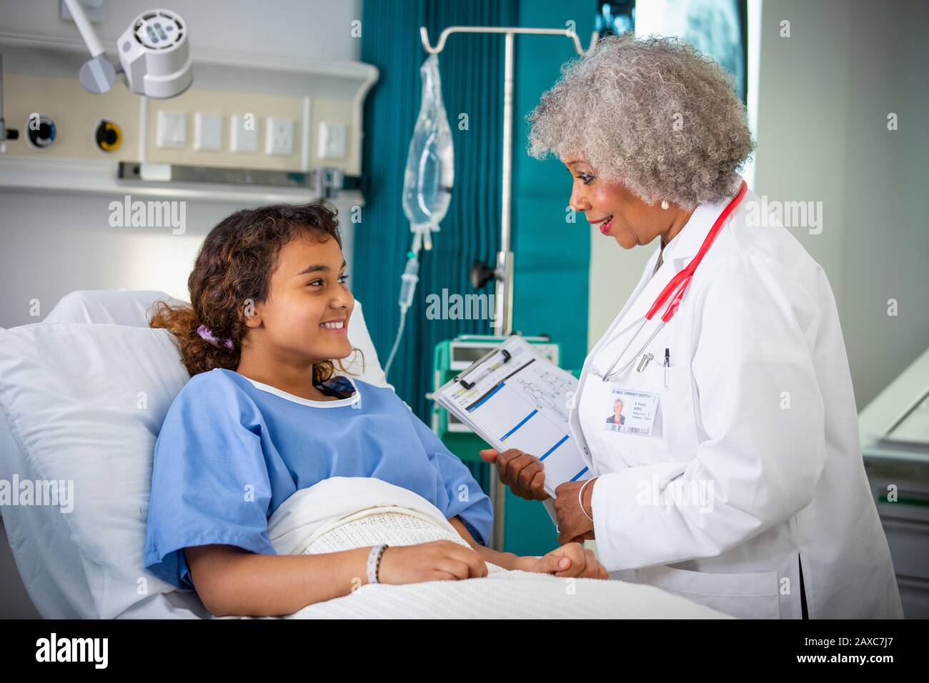Ärztin spricht mit Mädchen-Patientin im Krankenhauszimmer Stockfoto
