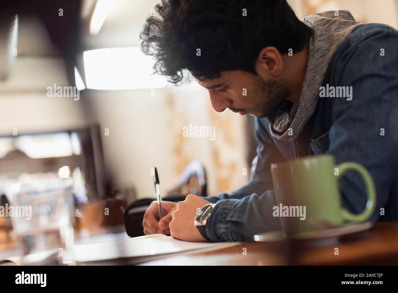 Konzentrierter junger Student der männlichen Universität, der im Café studiert Stockfoto