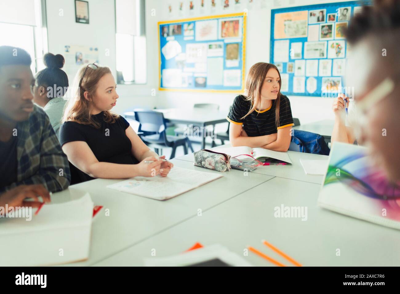 Schüler der Highschool sprechen und lernen am Tisch im Klassenzimmer Stockfoto