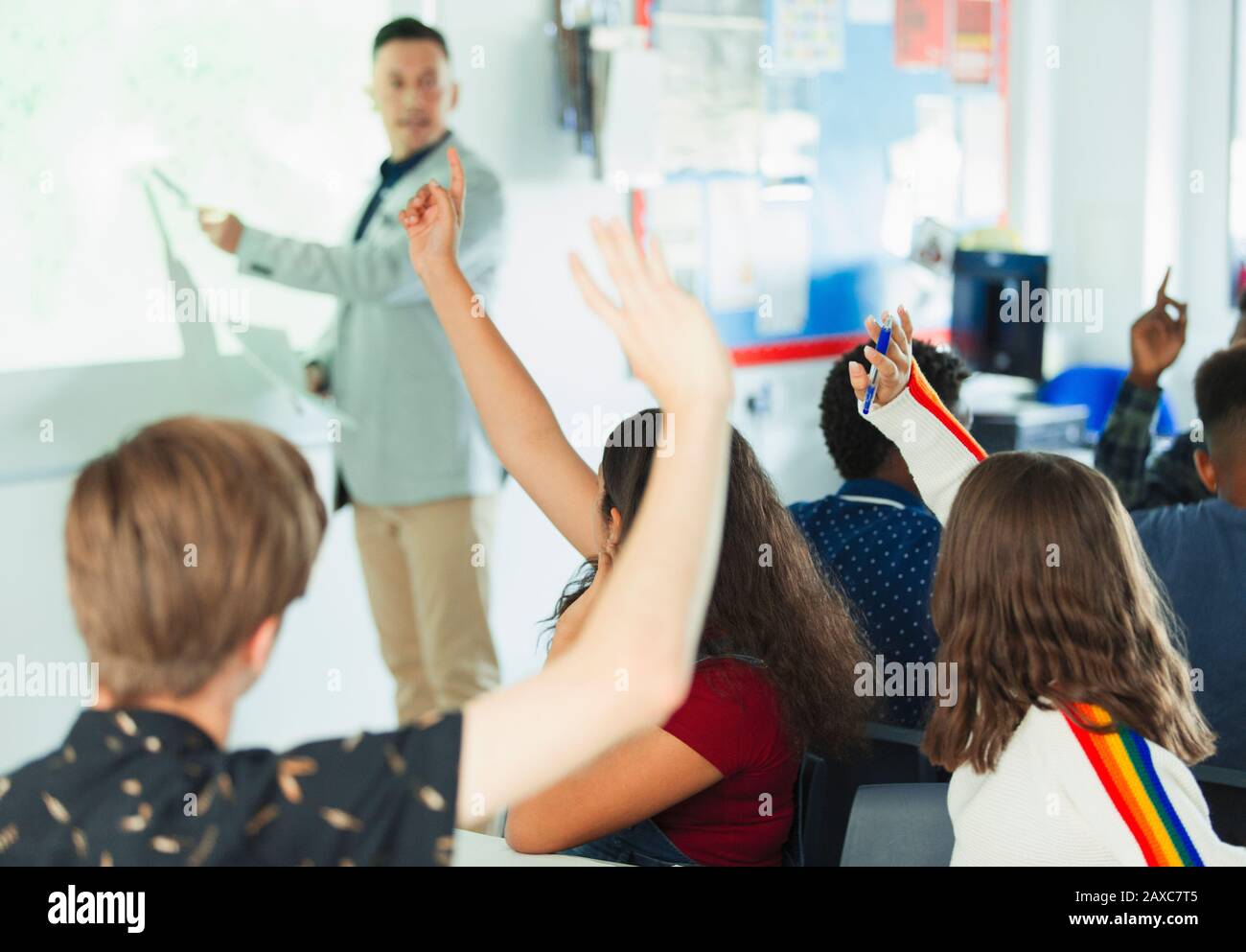 Schüler der High School mit erhobenen Händen während des Unterrichts im Klassenzimmer Stockfoto