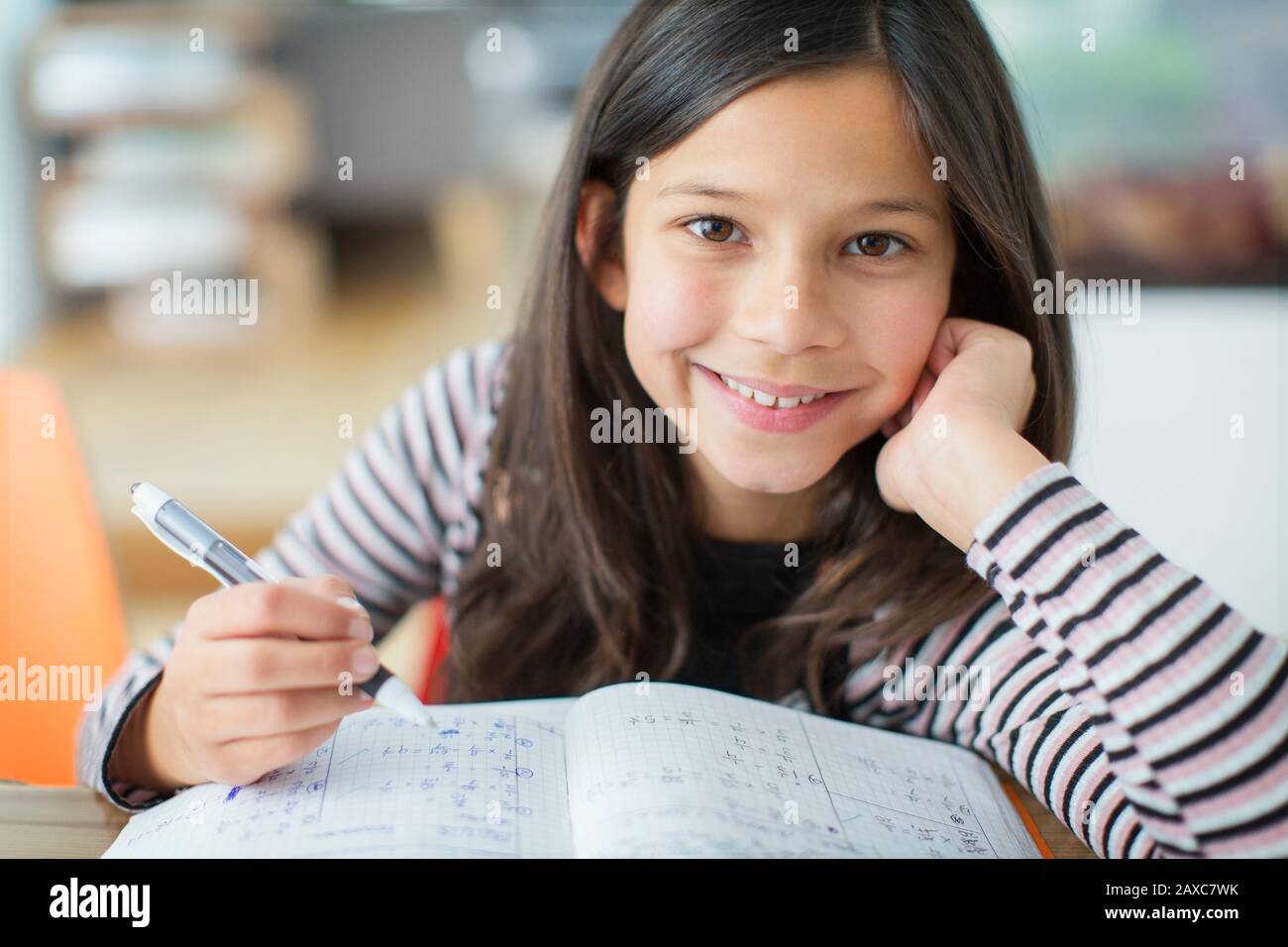 Portrait lächelnd, selbstbewusstes Mädchen, das Hausaufgaben macht Stockfoto