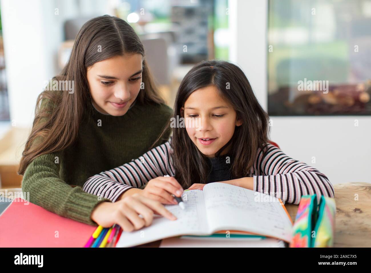 Mädchen hilft jungen Schwester bei Hausaufgaben Stockfoto