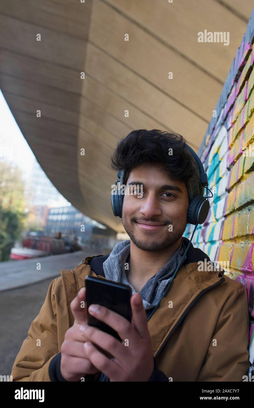 Portrait lächelnder junger Mann, der Musik mit Kopfhörern und mp3-Player hört Stockfoto
