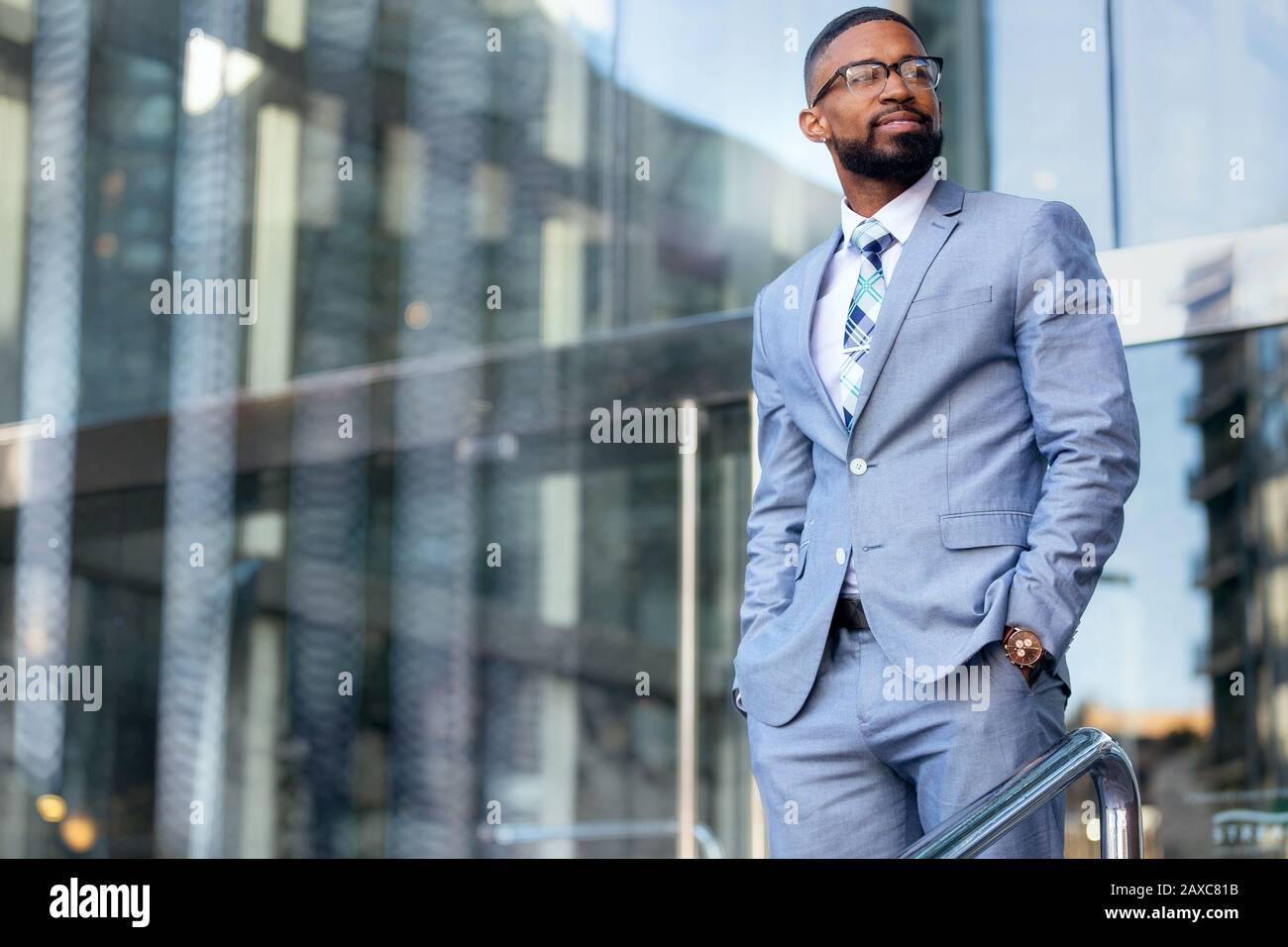 Gutaussehender CEO von African american Business man in einem stilvollen, schicken Anzug am Arbeitsplatz, selbstbewusst vor dem Finanzgebäude stehend Stockfoto