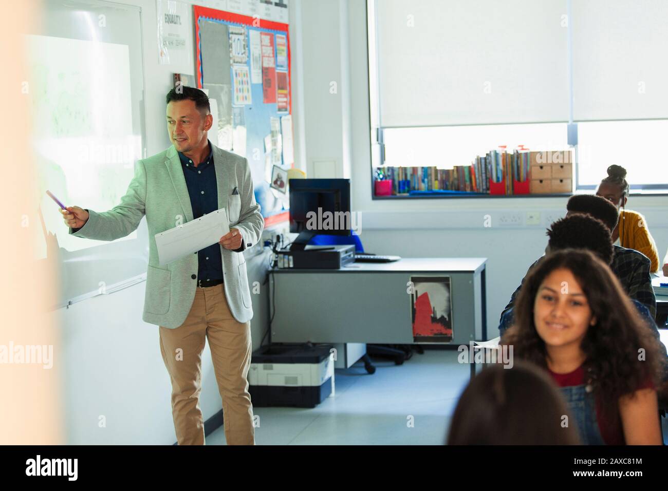 Männliche High-School-Lehrerin, die die Lektion auf der Projektionsleinwand im Klassenzimmer führt Stockfoto