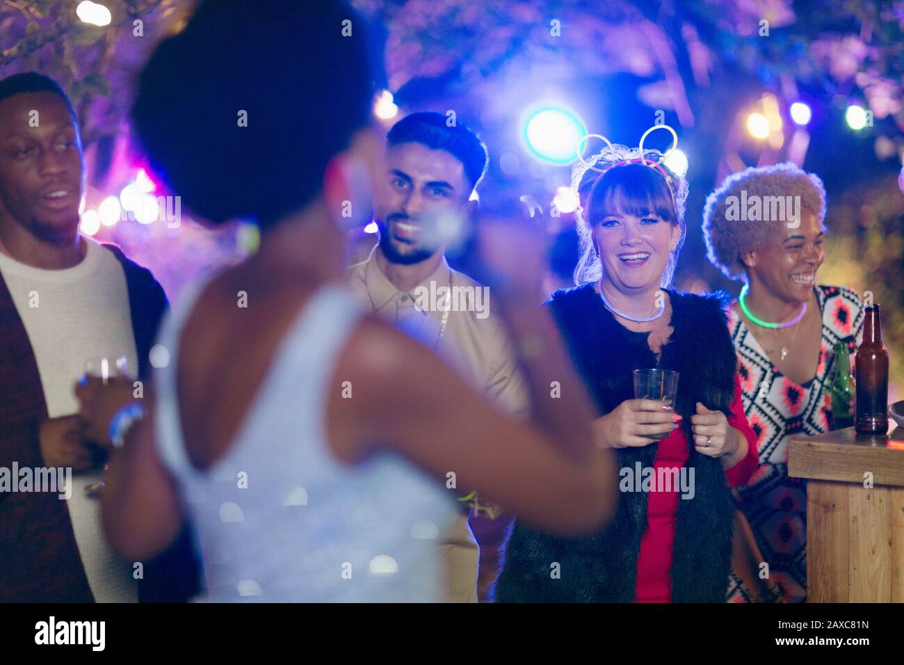Fröhliche Freunde trinken und singen Karaoke auf der Gartenparty Stockfoto