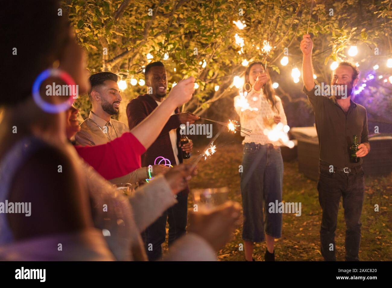 Verspielte Freunde mit Sparklern, die Gartenparty genießen Stockfoto