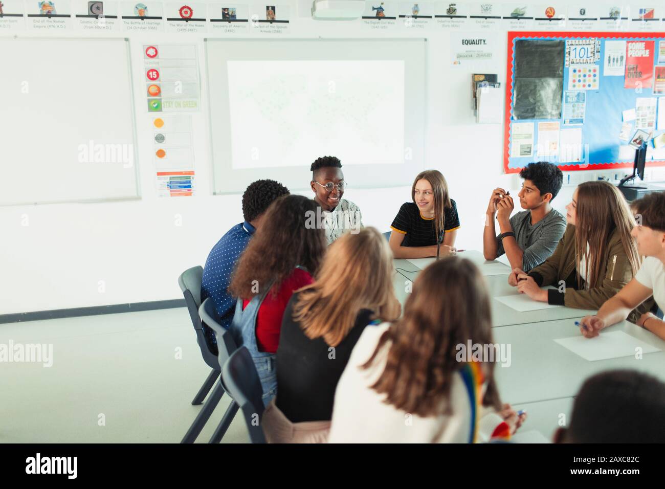 Schüler der High School, die in der Debattierklasse am Tisch sprechen Stockfoto