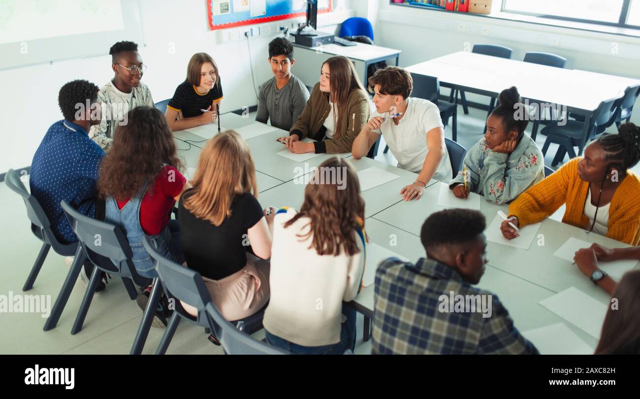 Schüler der High School, die in der Debattierklasse am Tisch sprechen Stockfoto