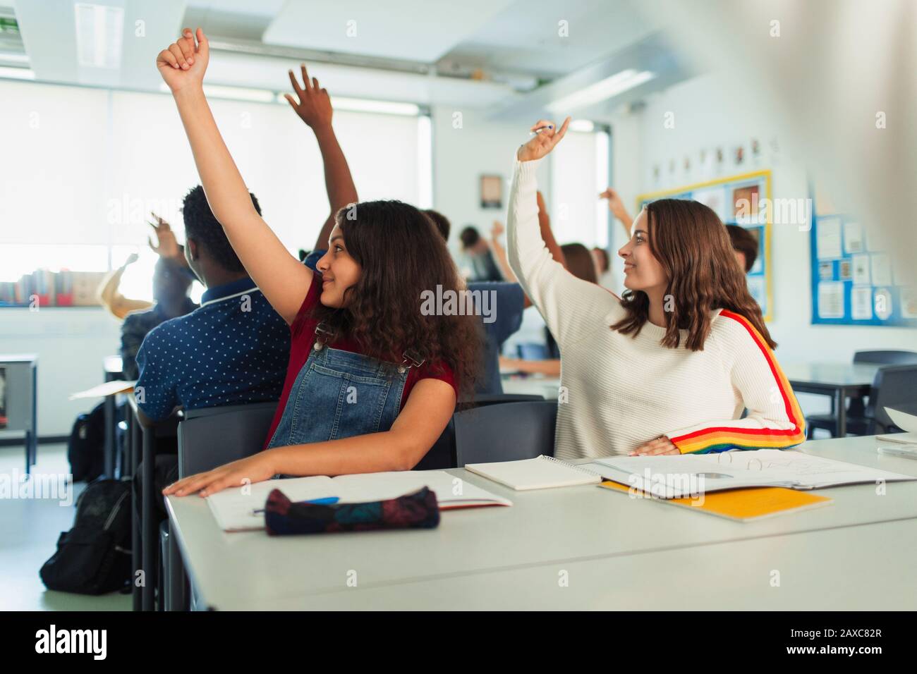 Schüler der High-School-Mädchen mit erhobenen Händen während des Unterrichts im Klassenzimmer Stockfoto