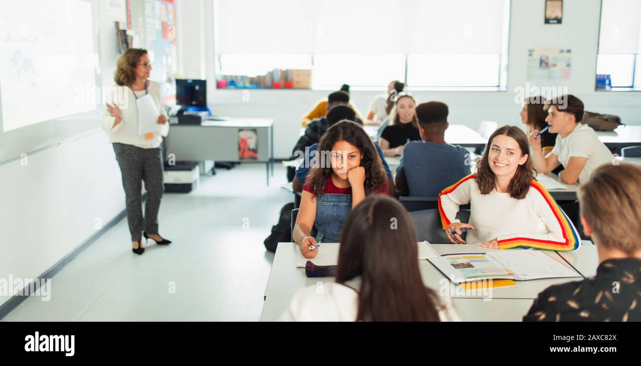 Schüler der High-School-Mädchen, die während des Unterrichts am Tisch im Klassenzimmer sprechen Stockfoto