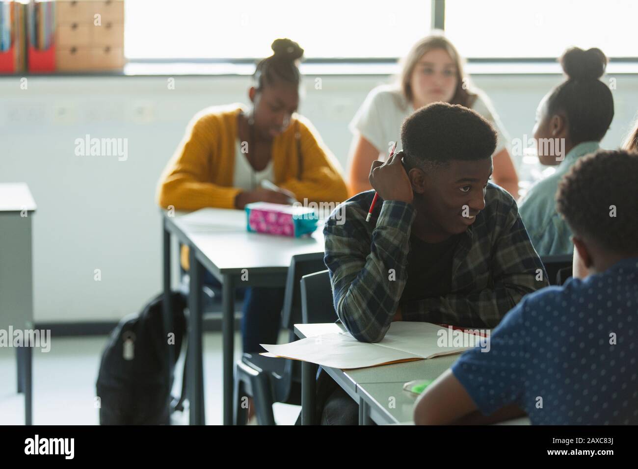 Schüler der High School machen Hausaufgaben und sprechen an Tischen im Klassenzimmer Stockfoto