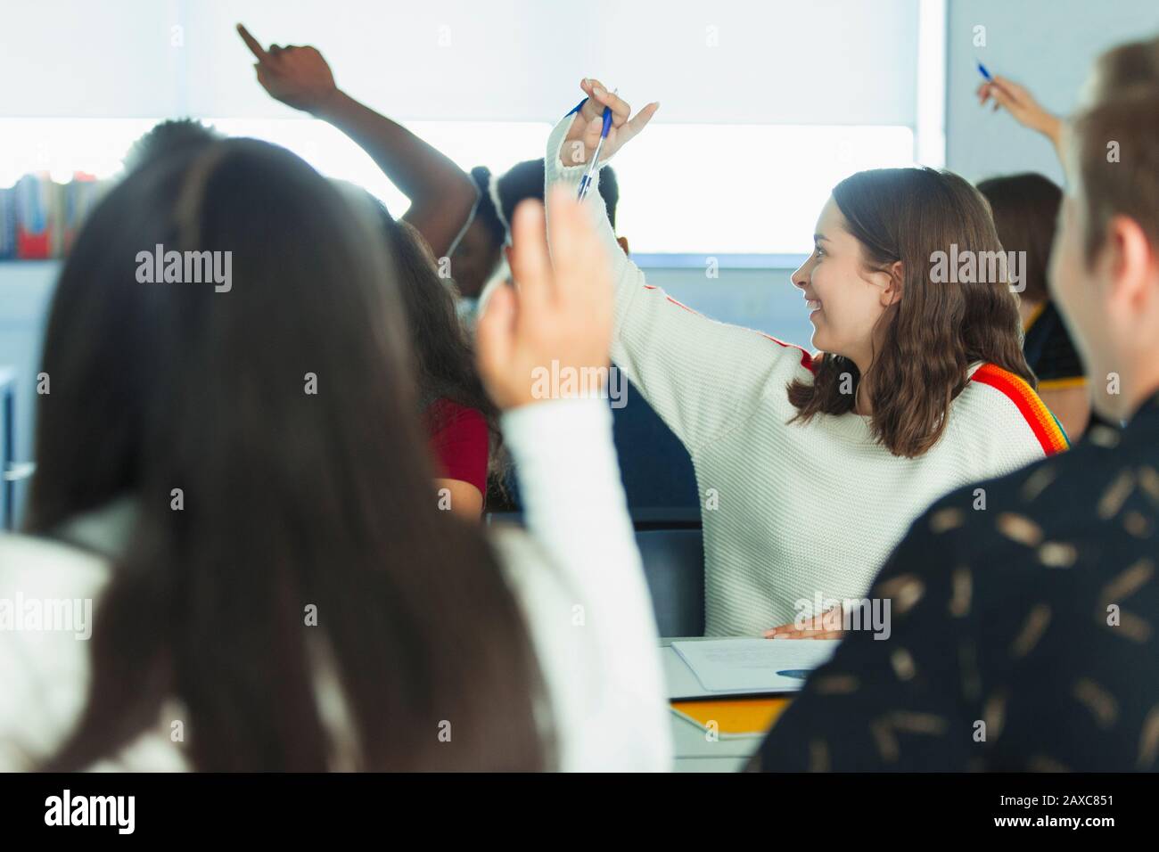 Schüler der High School mit erhobenen Händen im Klassenzimmer Stockfoto