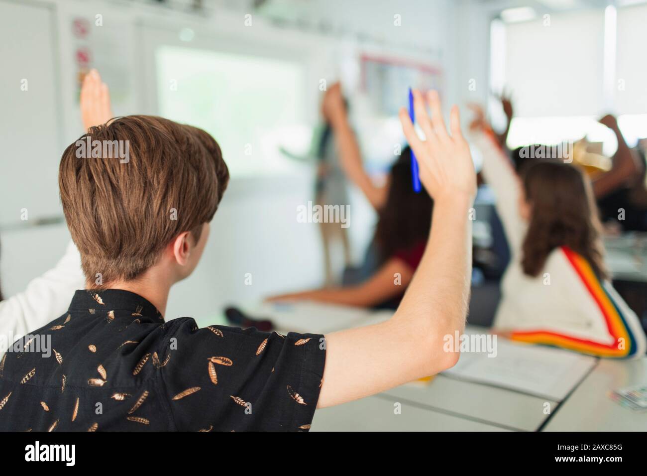 Schüler des High-School-Jungen mit erhobenen Händen während des Unterrichts im Klassenzimmer Stockfoto