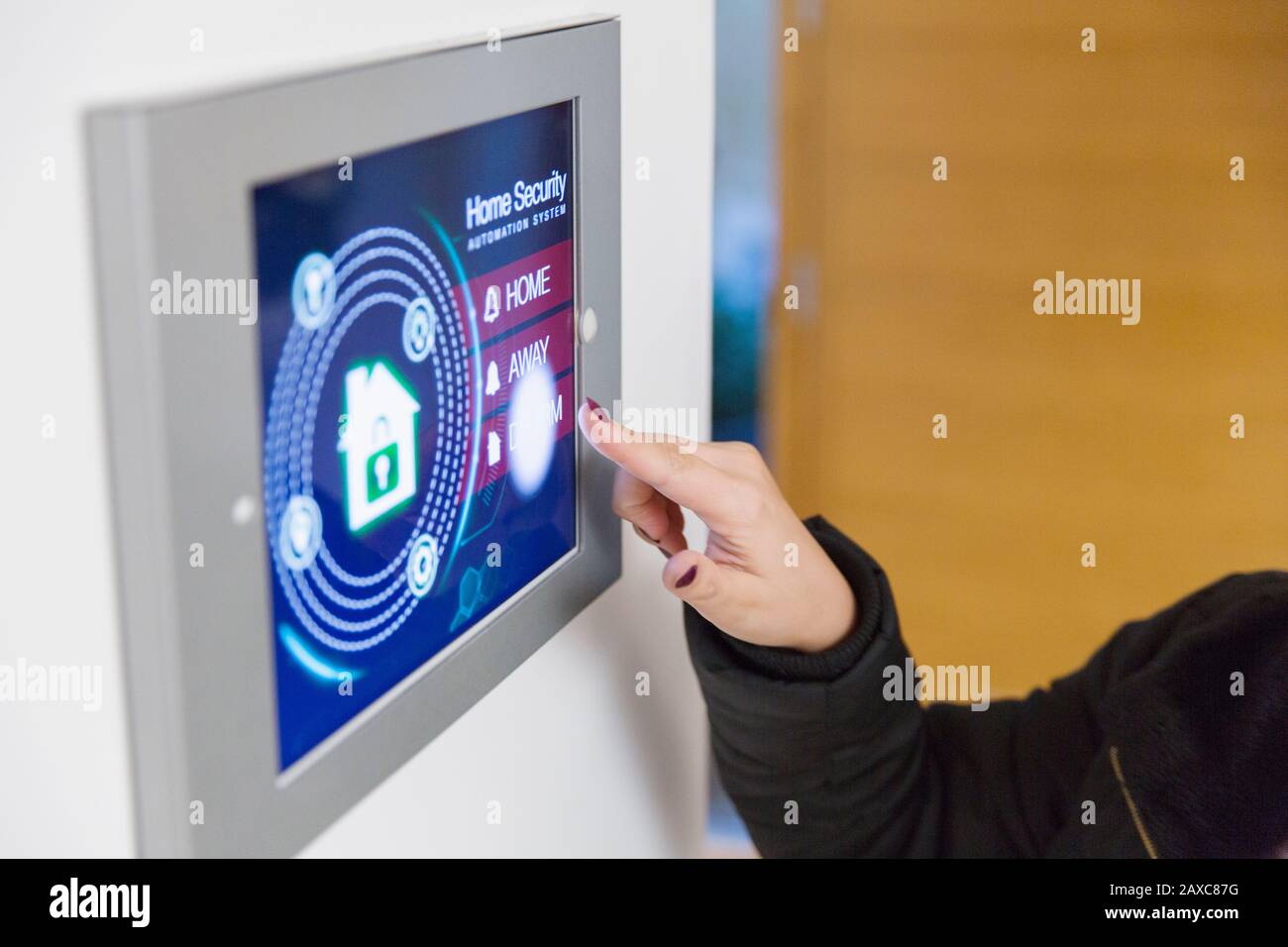 Frau, die einen intelligenten Alarm für die Sicherheit zu Hause auf dem Touchscreen auslöst Stockfoto