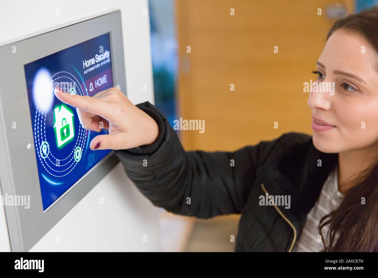 Frau, die einen intelligenten Alarm für die Sicherheit zu Hause auf dem Touchscreen auslöst Stockfoto