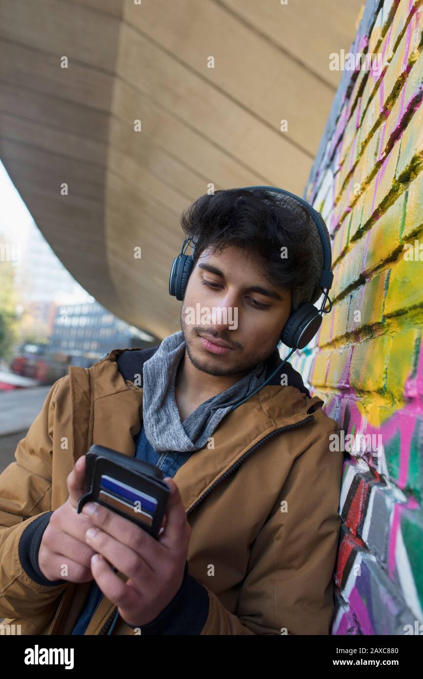 Junger Mann, der Musik mit Kopfhörern und mp3-Player hört Stockfoto