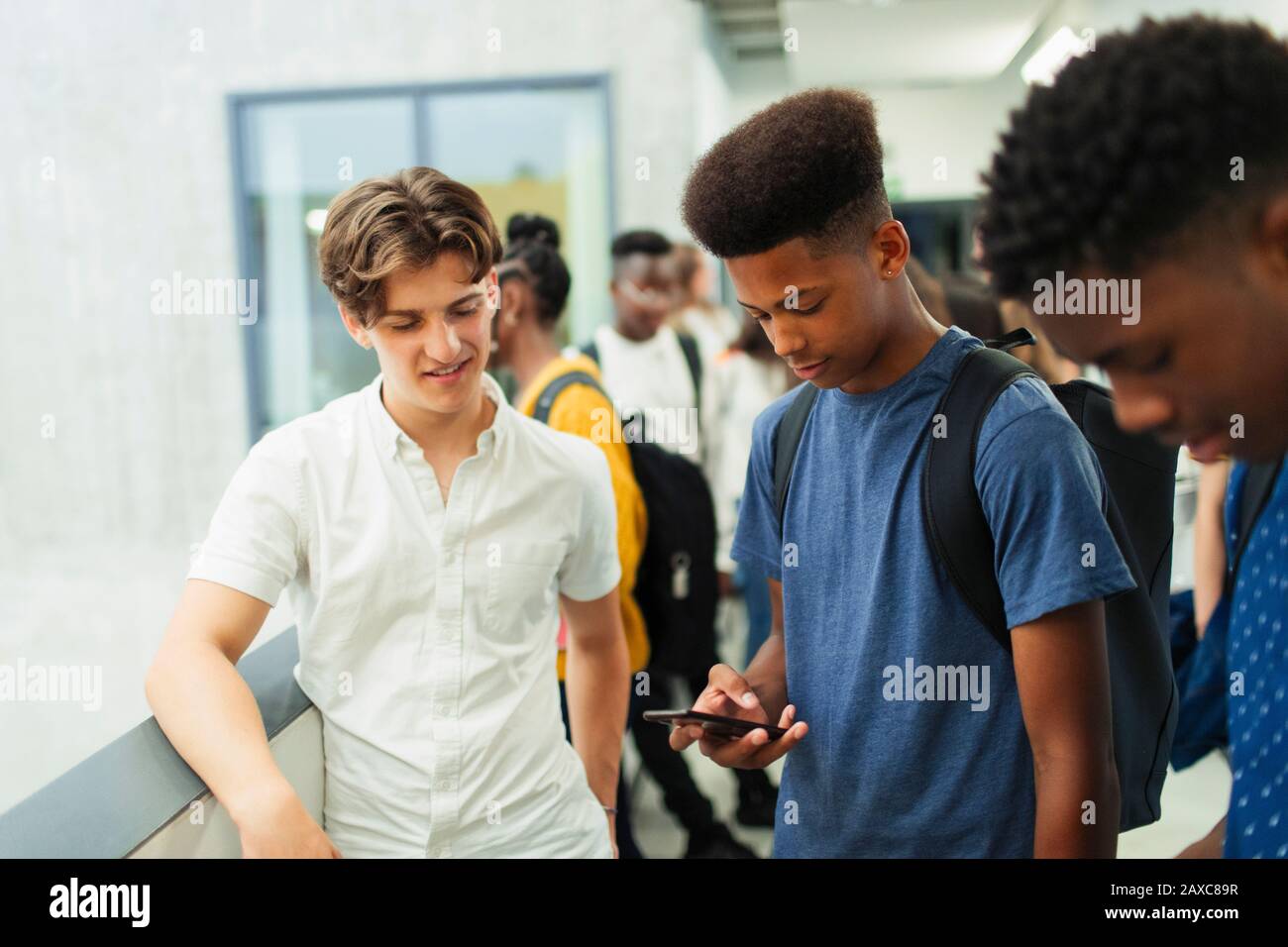 Junge Studenten mit Smartphone im Korridor Stockfoto