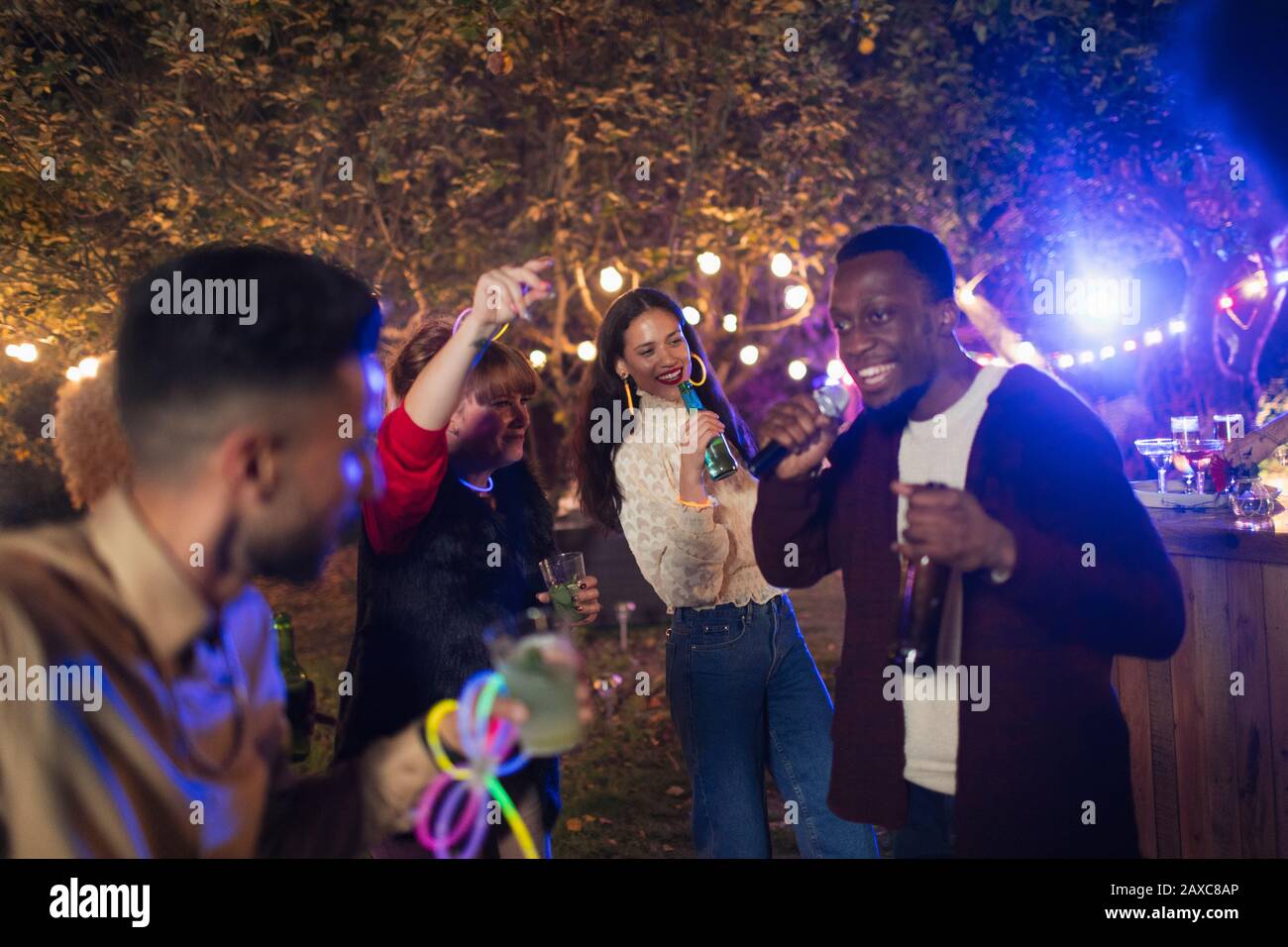 Freunde tanzen und singen Karaoke auf der Gartenparty Stockfoto