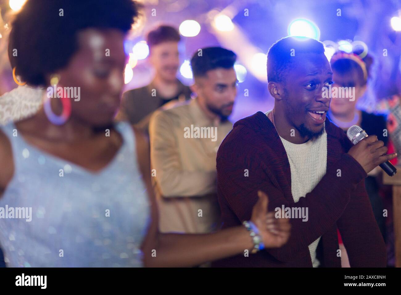 Freunde, die Karaoke unterschreiben und auf der Party tanzen Stockfoto