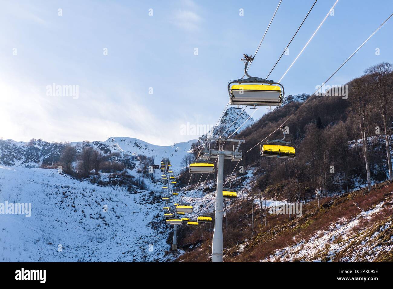 Skilift mit gelben Kabinen in einem Skigebiet in den Bergen gegen einen blauen Winterhimmel Stockfoto