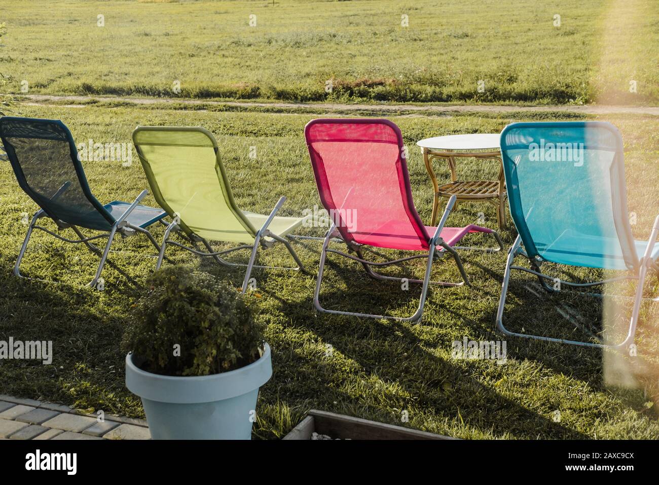 Vier mehrfarbige Sonnenliegen stehen draußen auf grünem Gras. Das Konzept der Erholung im Freien an einem ruhigen Ort Stockfoto