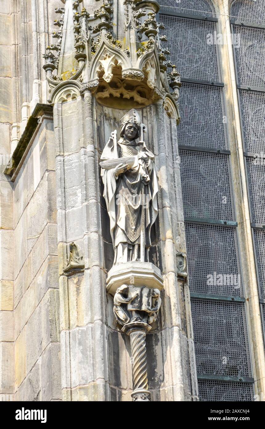 Detail der Außenfassade der St.-John-Kathedrale in Hertogenbosch, Nordbrabant, Niederlande. Holländische Gotik, größte katholische Kirche der Niederlande. Statue auf vertikalem Foto. Stockfoto