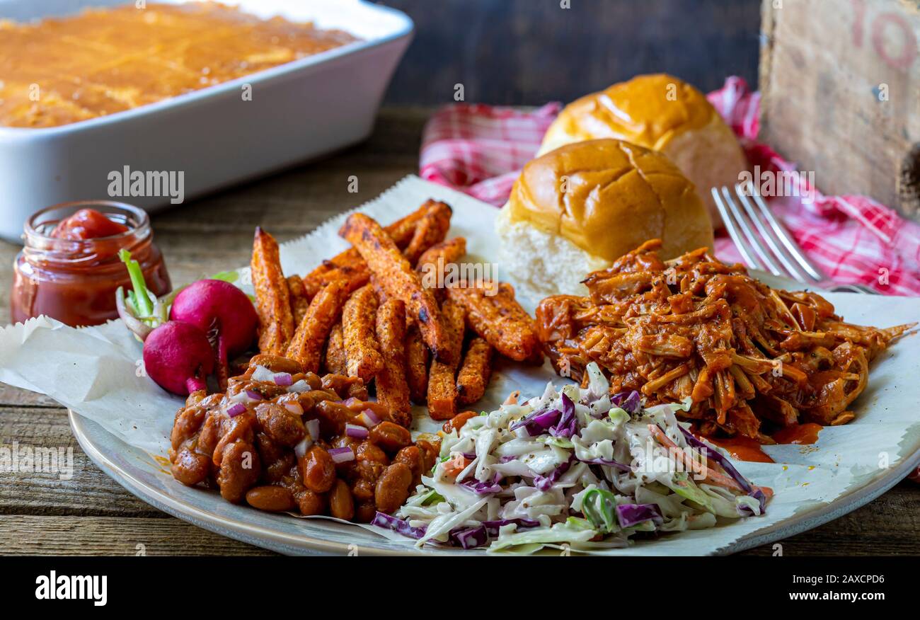 Südamerikanische Küche. Veganes Barbecue Jack-fruit, Coleslaw, Backofen gebackene würzige Süßkartoffeln und BBQ gebackene Bohnen. Stockfoto