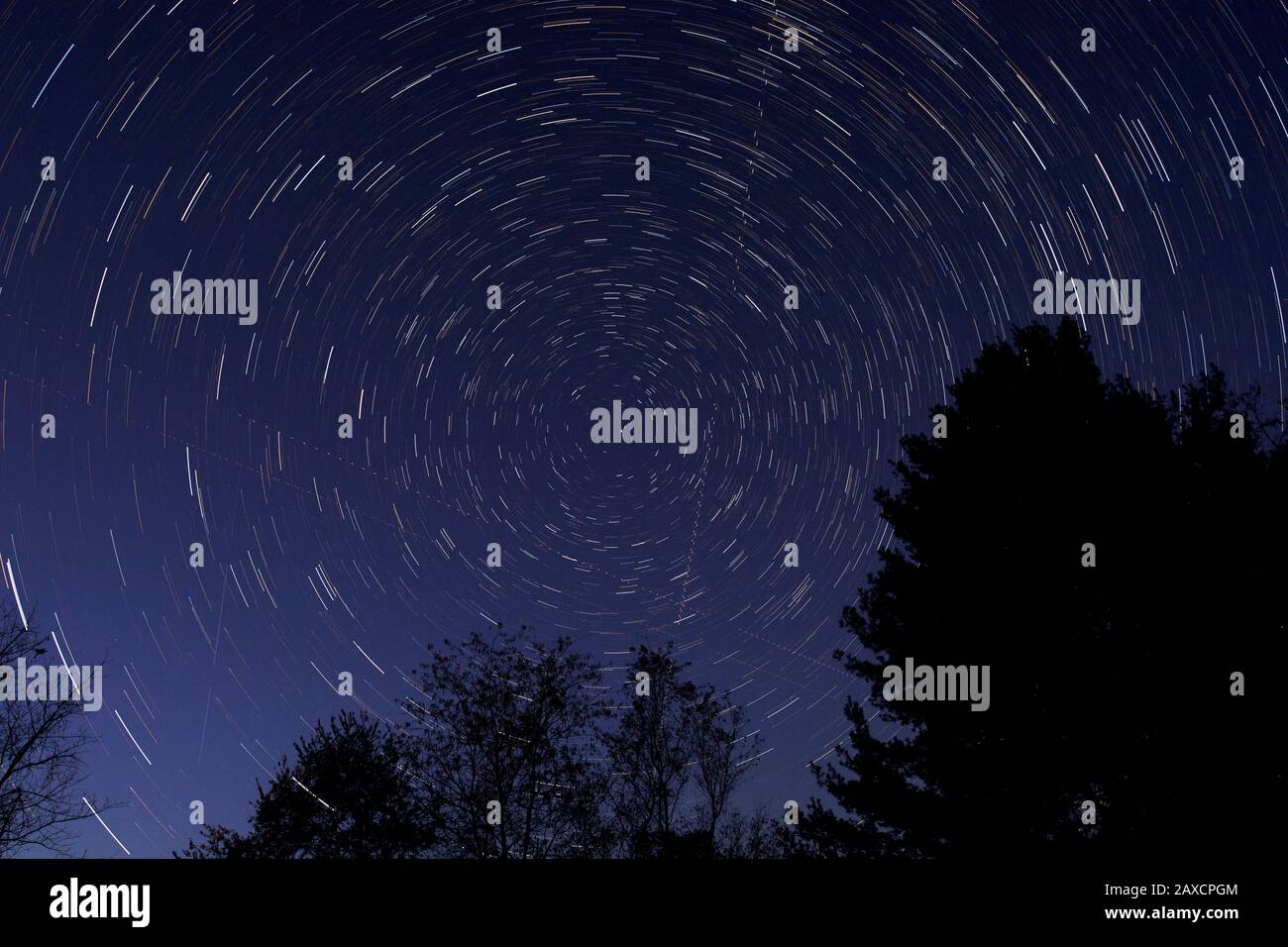 Nächtliches Zeitrafferfoto mit Mittelpunkt auf Nordstern (Polaris), das Sternenpfade und Flugbahnen zeigt. Stockfoto