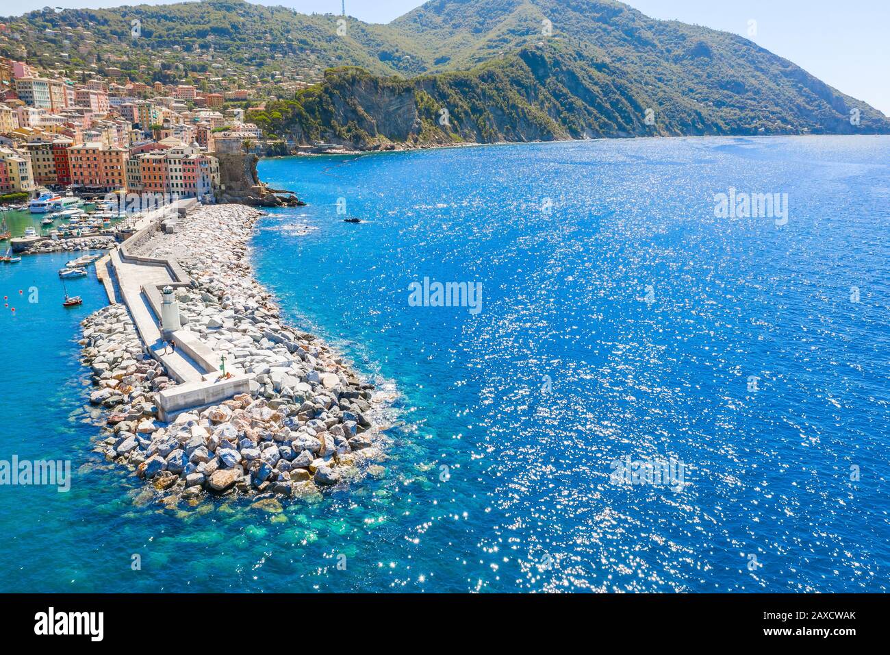 Luftaufnahme eines Wellenbrechens und eines Leuchtturms im ligurischen Meer mit Berg auf dem Hintergrund. Camogli bei Genua, Italien. Türkisblaues Wasser auf dem Stockfoto
