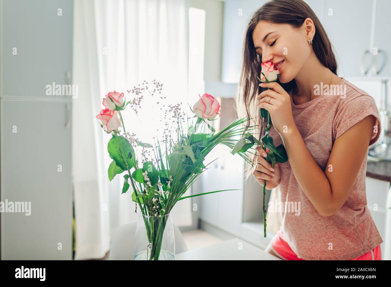 Valentinstag, Frauentag. Frau riecht Blumenstrauß von Rosen, die von Freund begabt wurden. Geschenk für den Urlaub Stockfoto