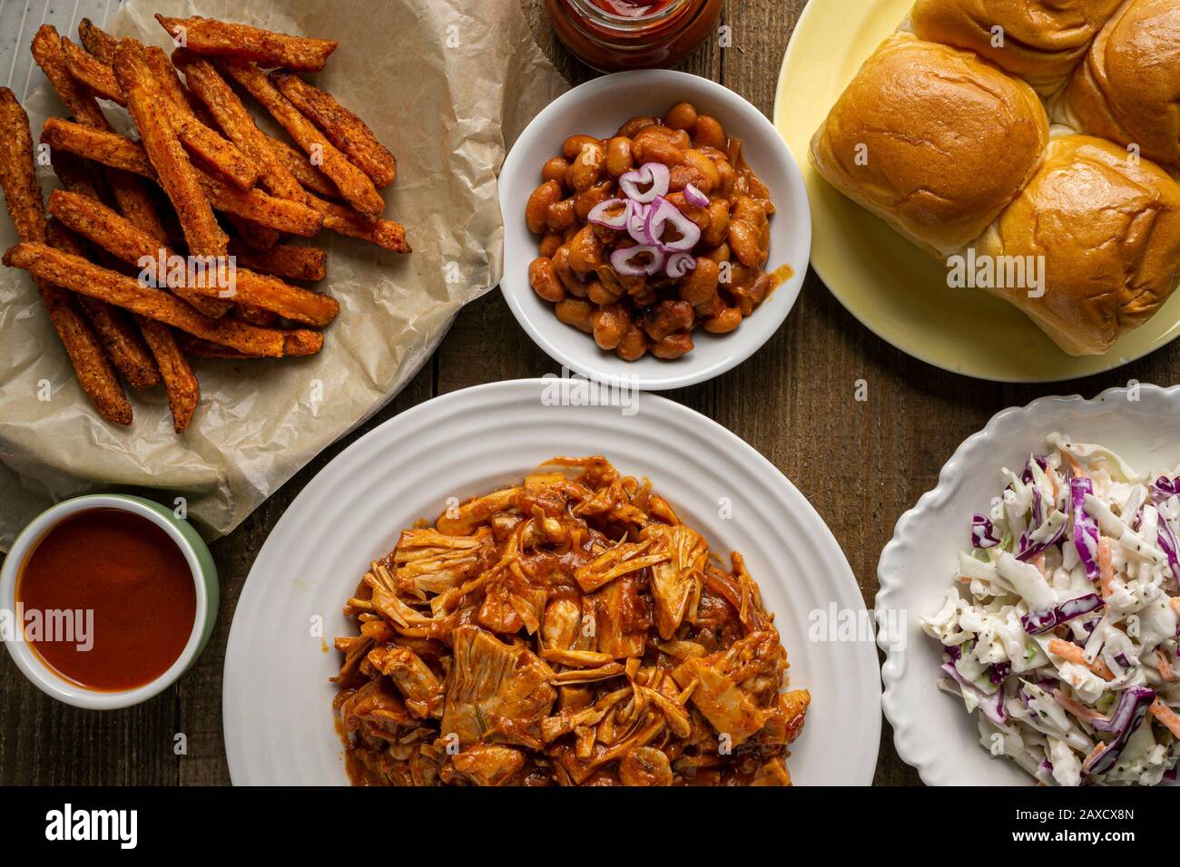Veganer Grillplatz. Gebackene Bohnen im Südstaaten-Stil, Coleslaw, Brötchen zum Abendessen und Pommes frites. Stockfoto