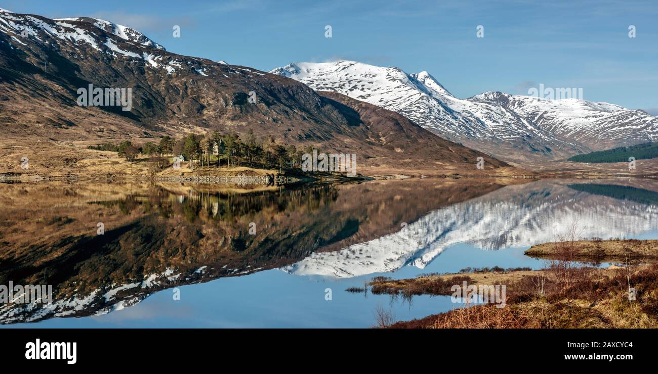 Schneebedeckte Berge und Hügel spiegeln sich in Loch Cluanie, Glen Sheil, Scottish Highlands wider Stockfoto
