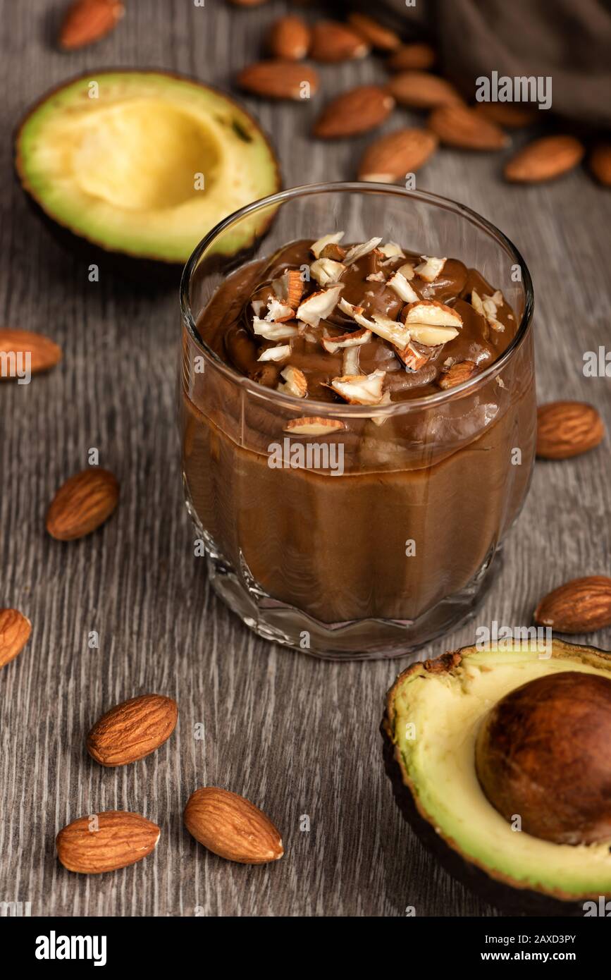 Avocado-Dessert mit Kakao in einem Glas auf einer Holzoberfläche. Vegane Rohprodukte. Stockfoto