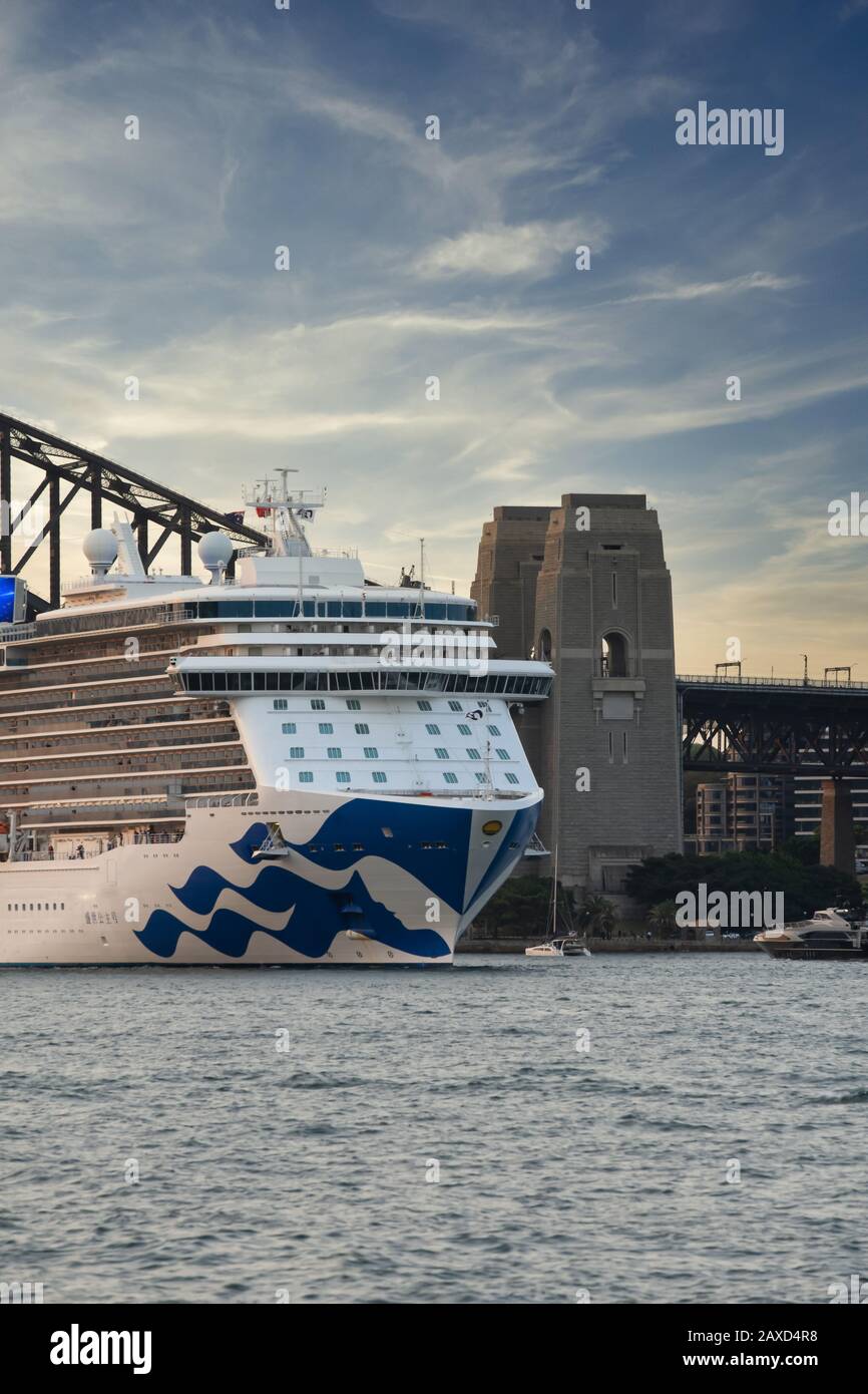 Majestätisches Kreuzfahrtschiff mit Princess, das den Hafen von Sydney bei Sonnenuntergang mit der Sydney Harbour Bridge im Hintergrund verlässt Stockfoto