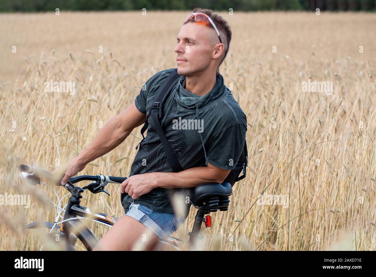 Ein Mann auf einem Feld auf einem Fahrrad. Vor dem Hintergrund des Himmels. Stockfoto