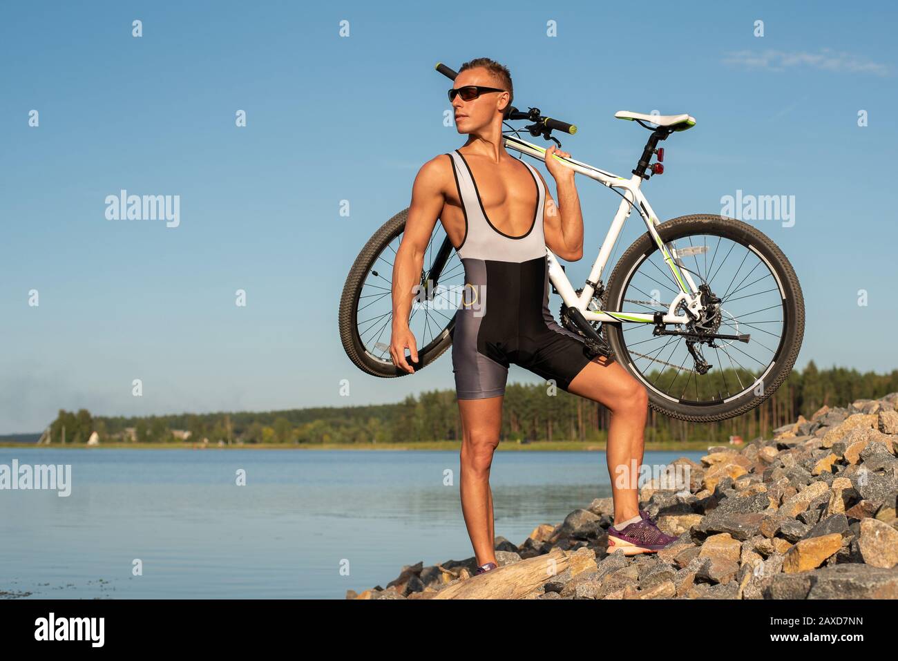 Ein Mann mit einem Fahrrad am Seeufer. Stockfoto