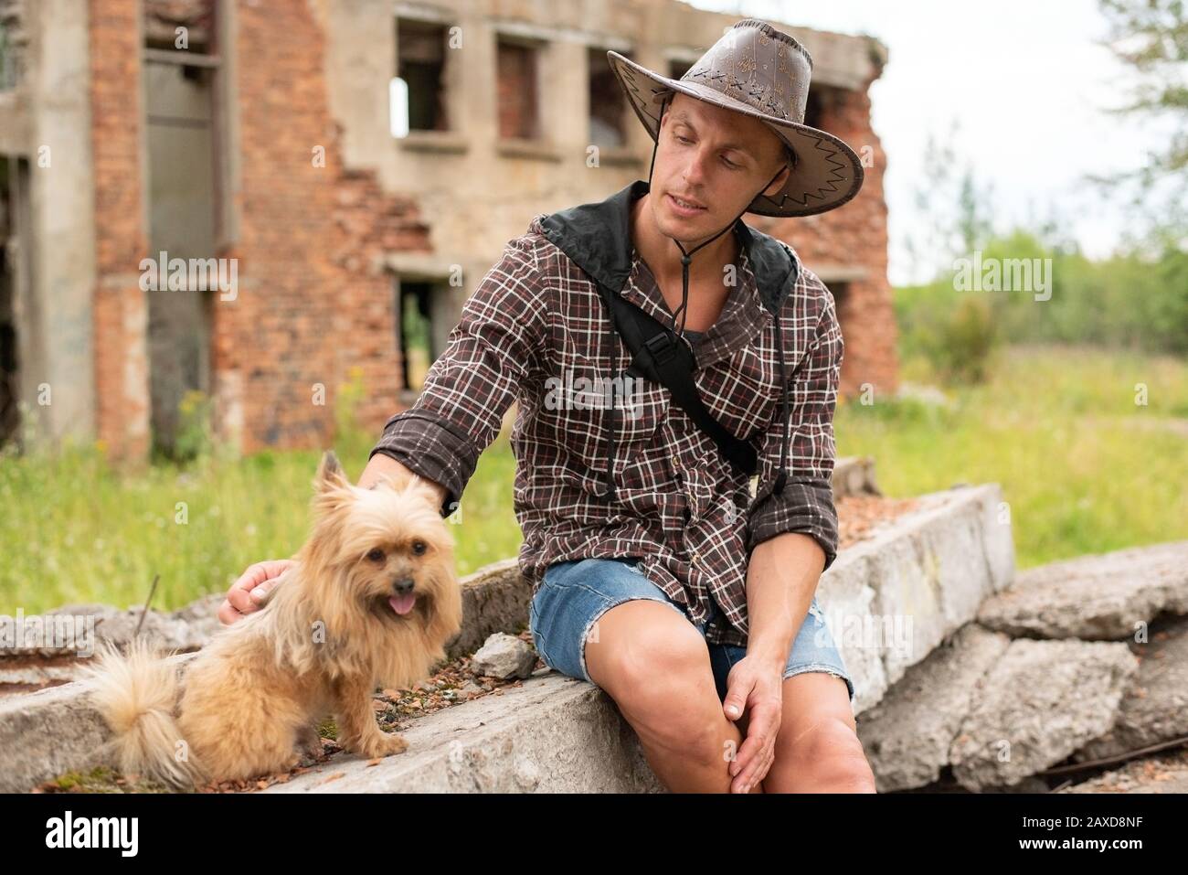 Ein Mann in einem Cowboyhut sitzt inmitten eines zerstörten Hauses. Stockfoto