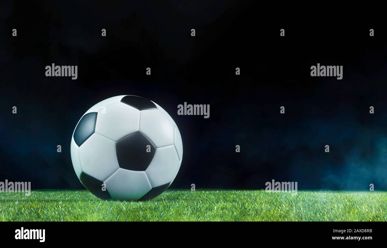 Traditioneller Fußball auf einem beleuchteten, leeren Sportplatz bei Nacht, beleuchtet von hellen Scheinwerfern in einem niedrigen Blickwinkel mit Schatten, Nebel und Kopieraum f Stockfoto