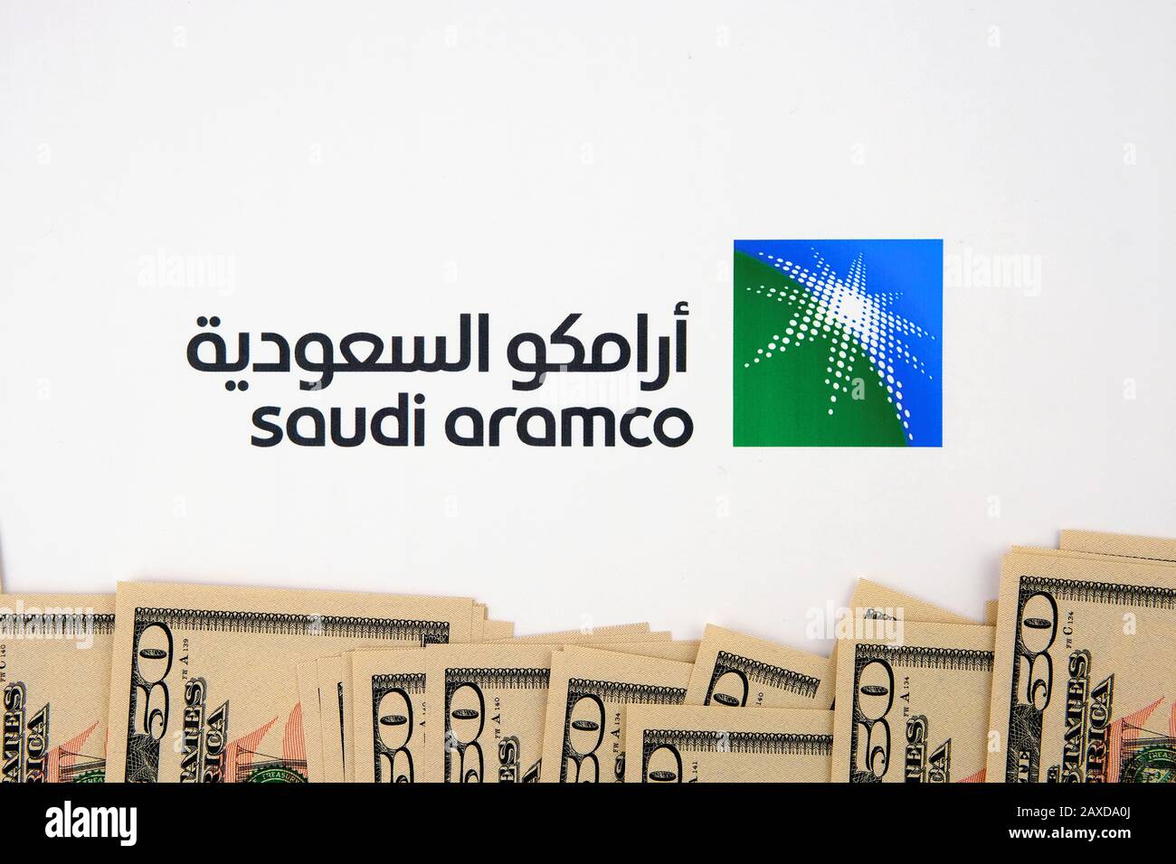 Saudi Aramco Logo und Stapel von Dollarscheinen. Die Saudi Arabian Oil Company ist eines der größten Unternehmen der Welt, das mit Einnahmen zu den Unternehmen gehört. Stockfoto