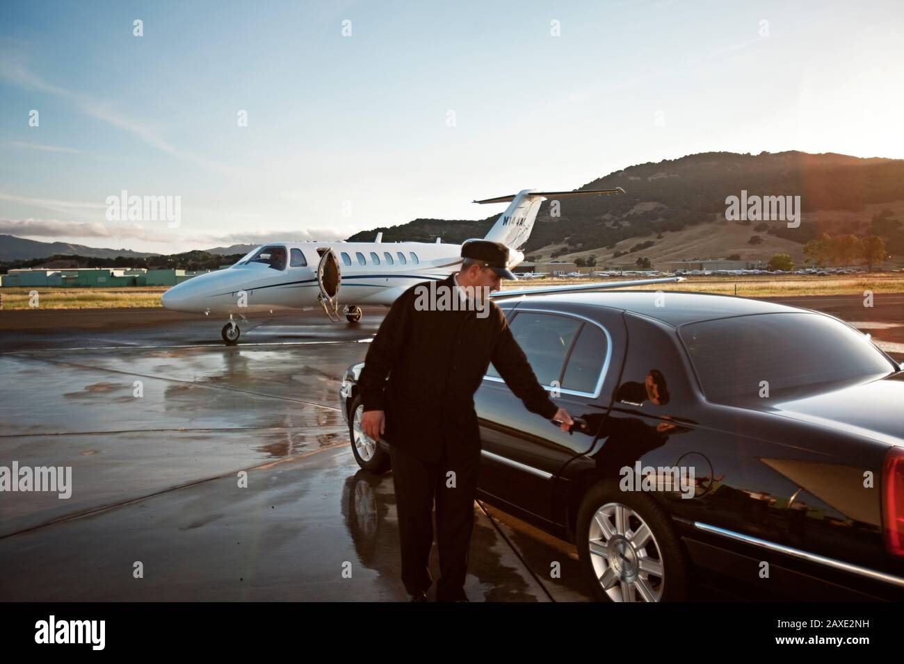 Chauffeur, der eine Autotür am Flughafen öffnet Stockfoto