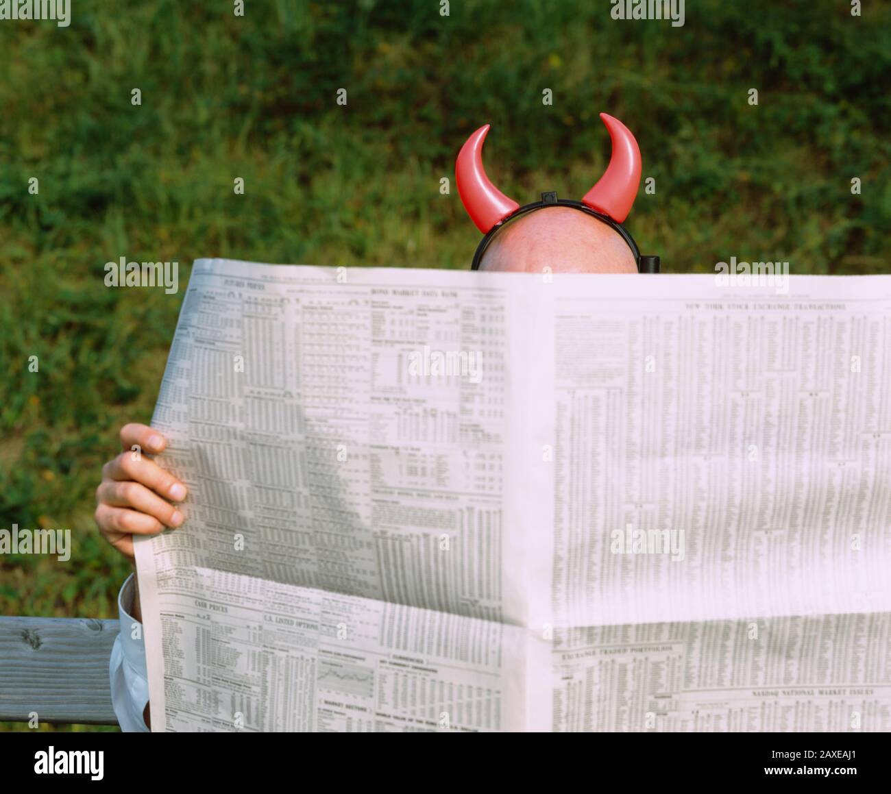 Mann mit Teufelshörnern liest Zeitung, Deutschland Stockfoto