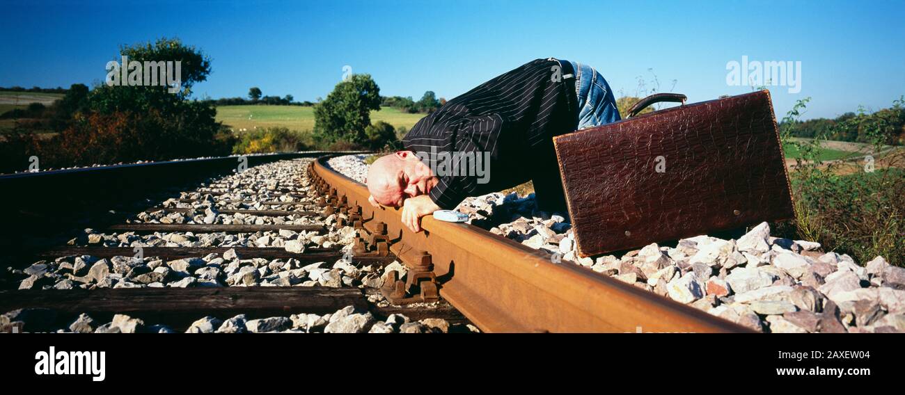 Reifer Mann, der seinen Kopf auf eine Eisenbahntrasse legt, Deutschland Stockfoto