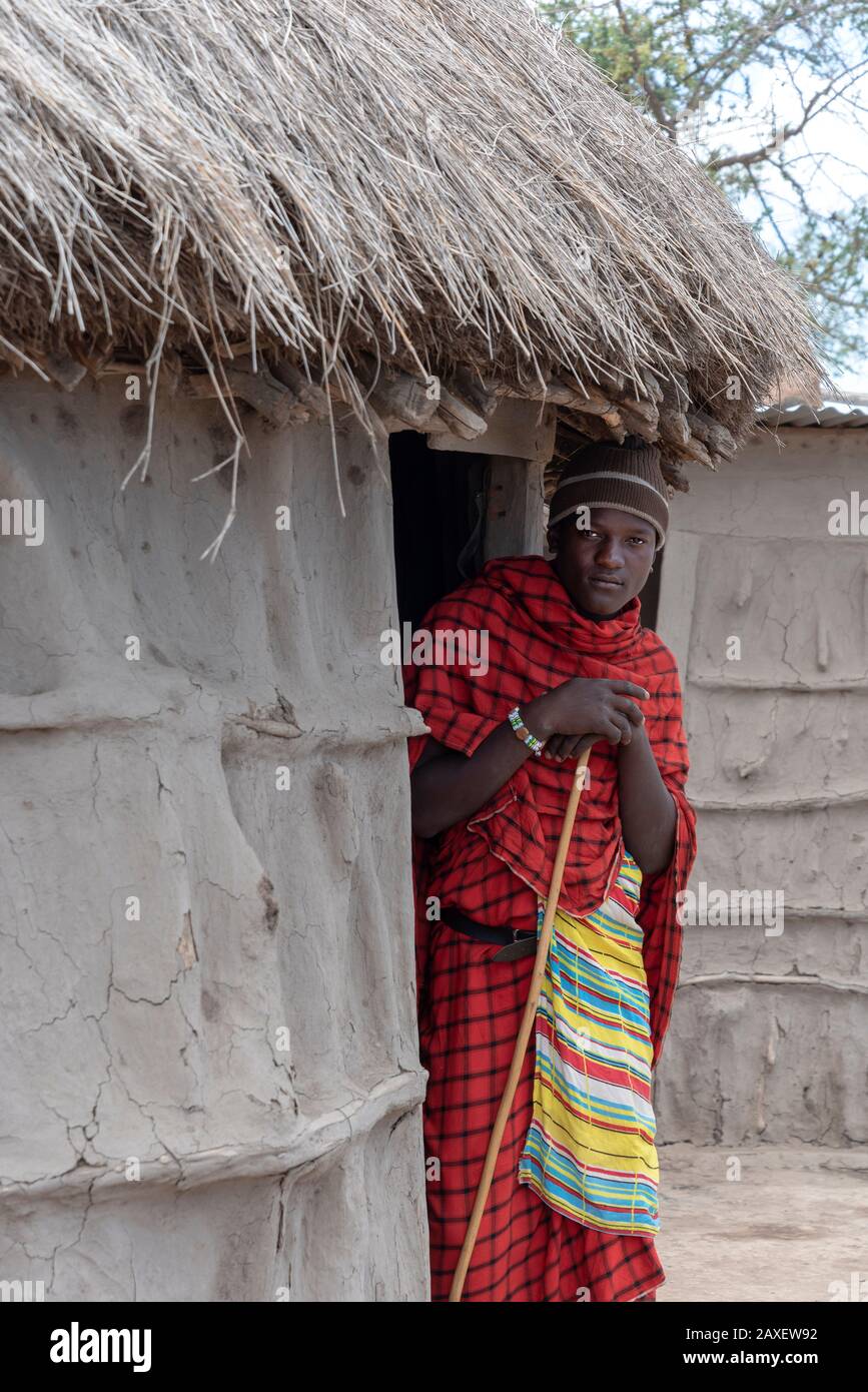 Schöne junge Masaai Warrior vor seiner traditionellen Hütte Stockfoto