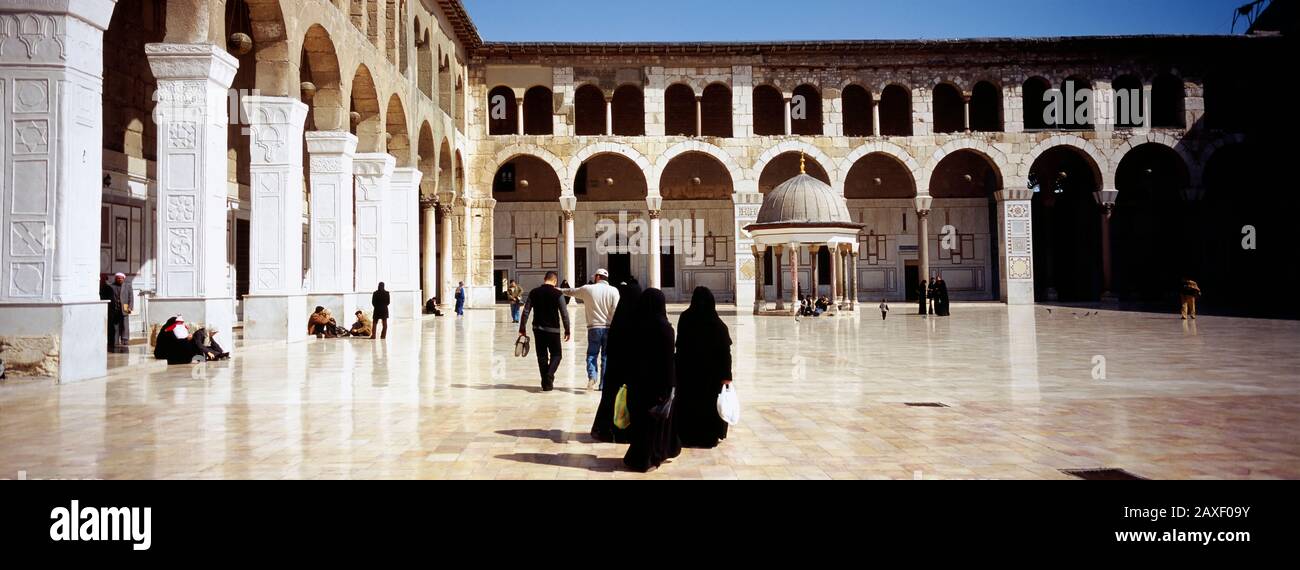 Eine Gruppe von Menschen, die im Innenhof einer Moschee, der Umayyaden-Moschee, Damaskus, Syrien spazieren gehen Stockfoto