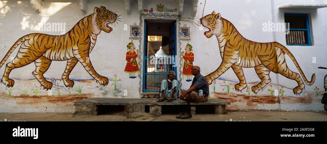Zwei reife Männer sitzen vor einer Tür eines Gebäudes, Udaipur, Rajasthan, Indien Stockfoto